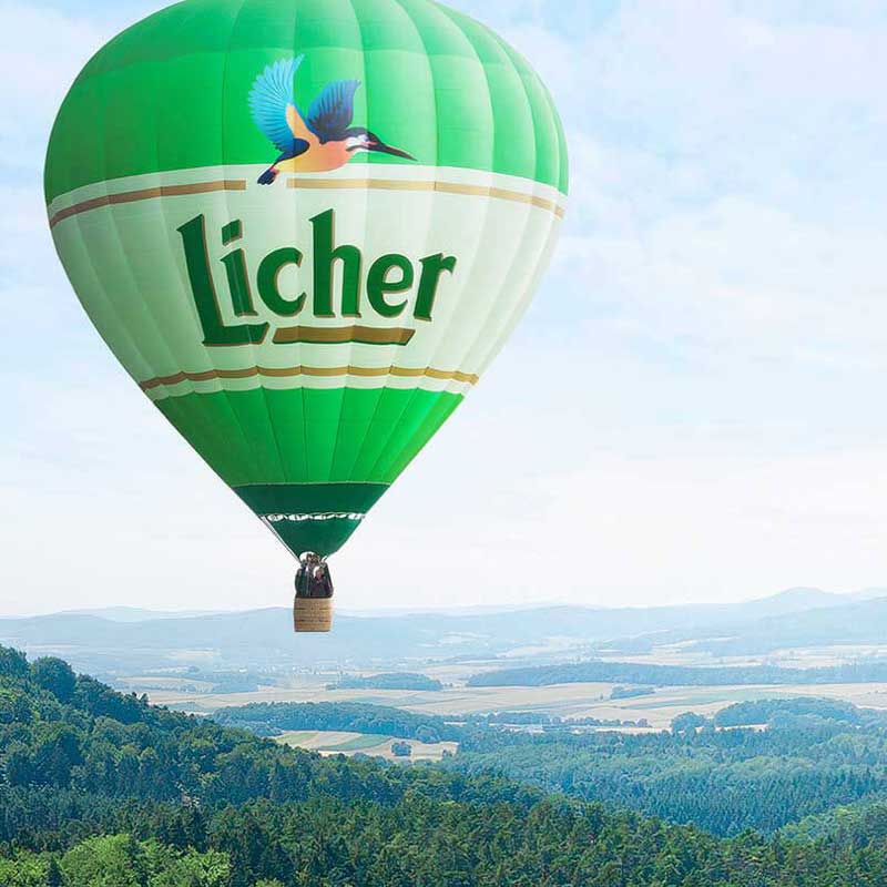 Großer grüner Licher Heißluftballon über einer malerischen Landschaft – Werbekampagne für Licher Brauerei.